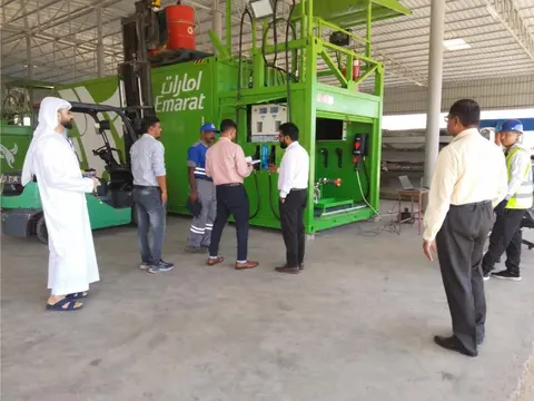 Customer representatives inspecting the green Emarat mobile fueling unit in the workshop
