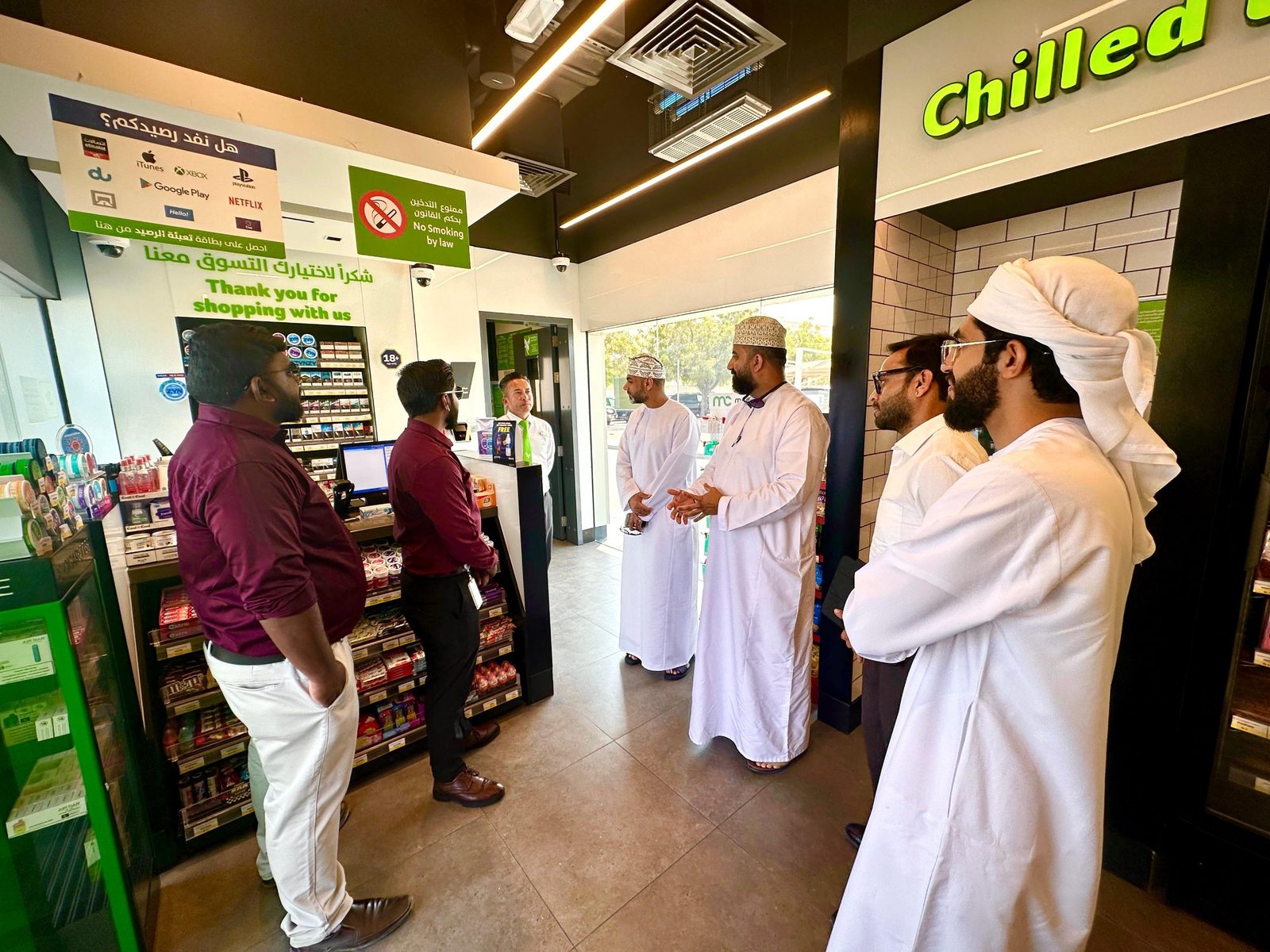 Visitors touring the shop of an Emarat service station with station staff