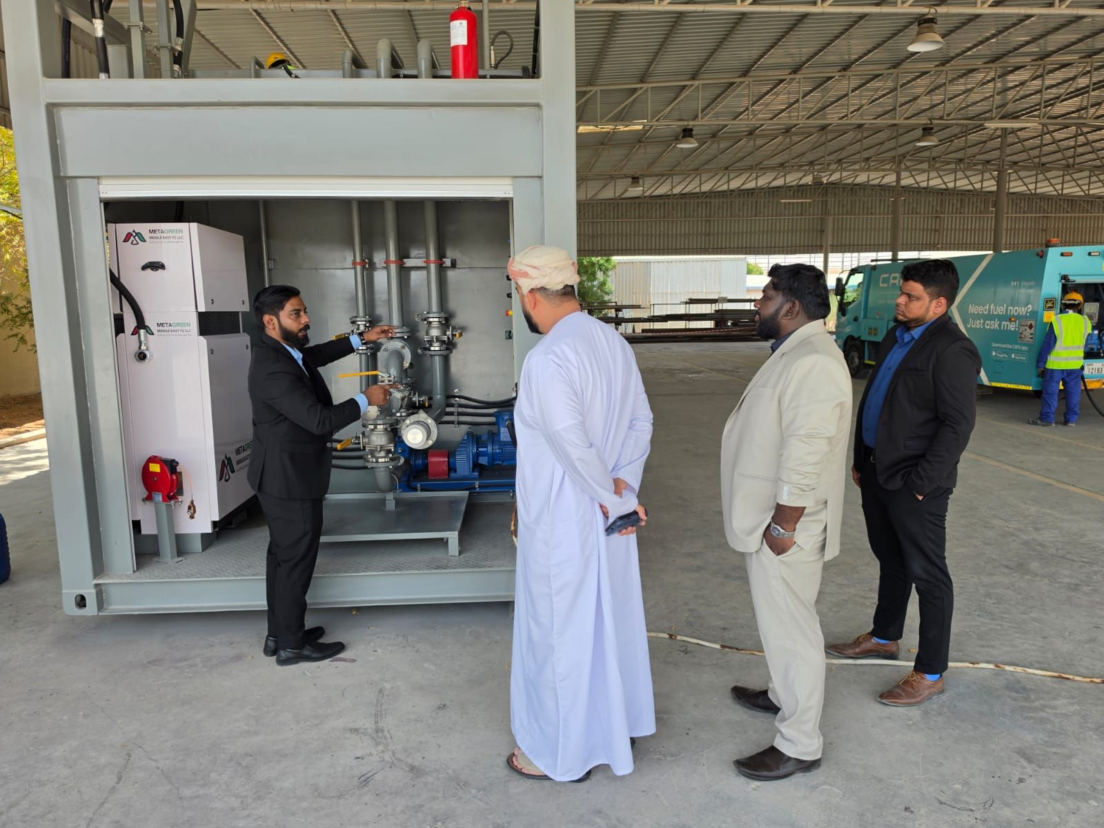 Engineer explaining the pump, valves and fuel-management cabinet of the demo unit to visiting client representatives